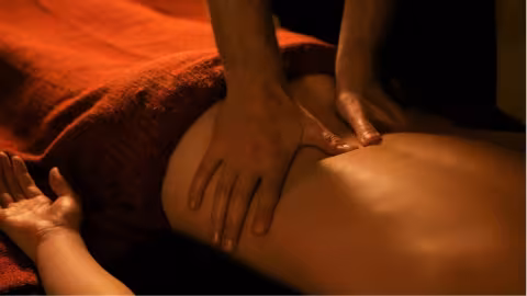 A serene spa massage session with a woman relaxing on a table, receiving a calming back massage.